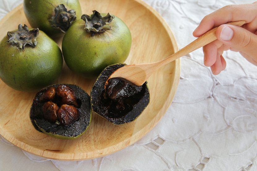 Frutos de zapote negro en un cuenco de madera