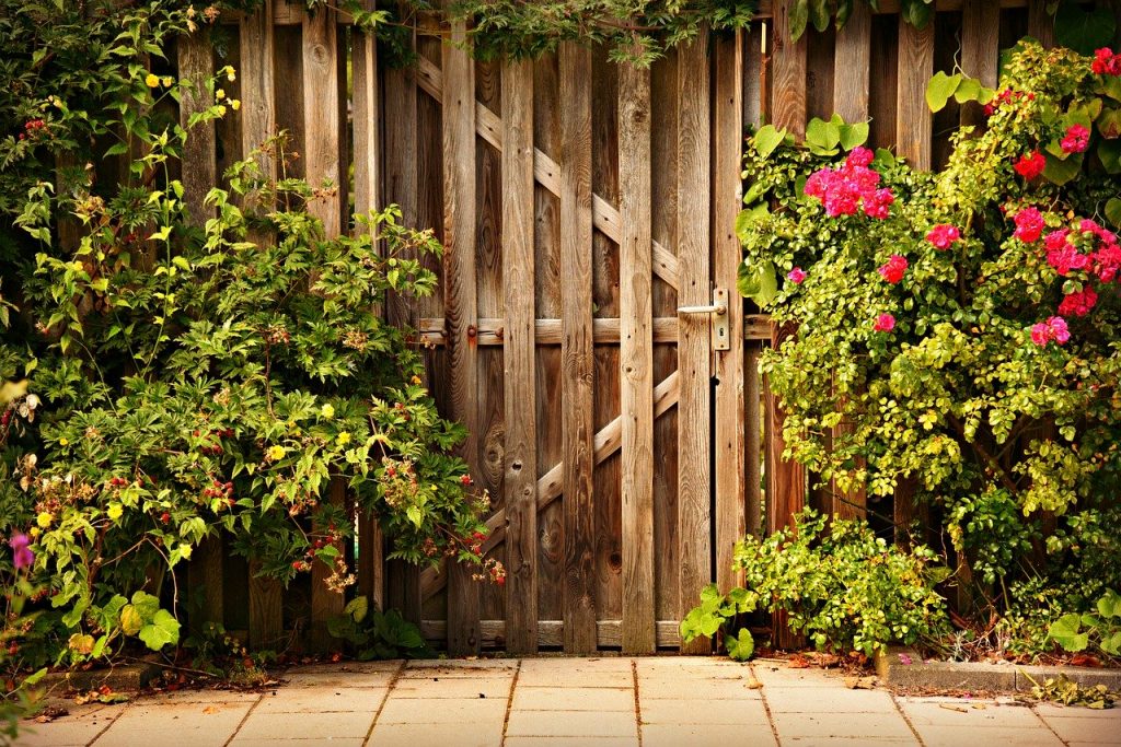 Puerta de jardín cerrada en un cerramiento de madera con vegetación