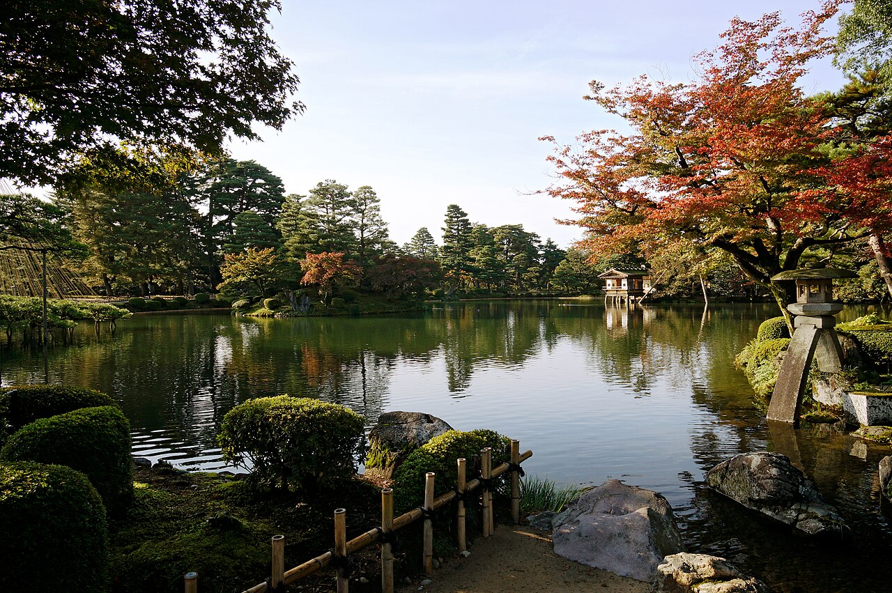 Jardín japonés con estanque, arces de otoño y pinos recortados