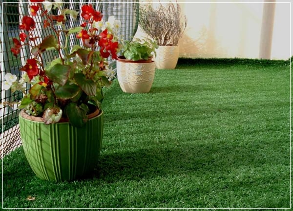 Jardinera con césped y plantas en el suelo de un balcón